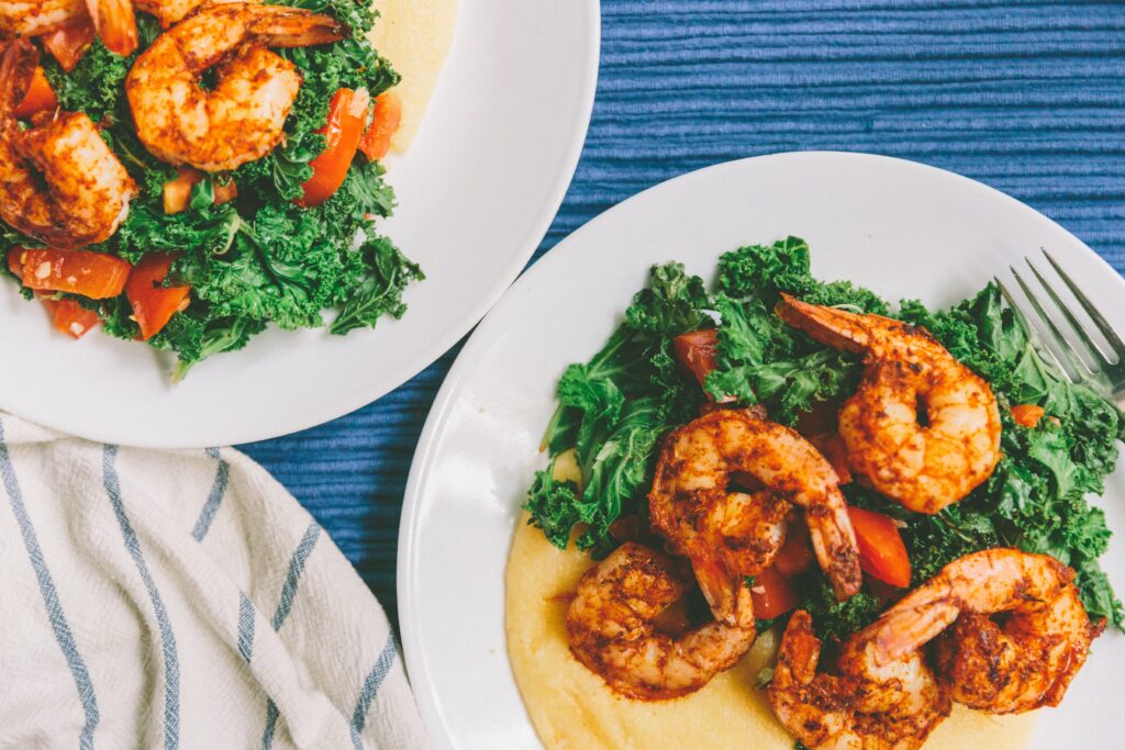 Two bowls of shrimp and grits on a blue corduroy tablecloth.