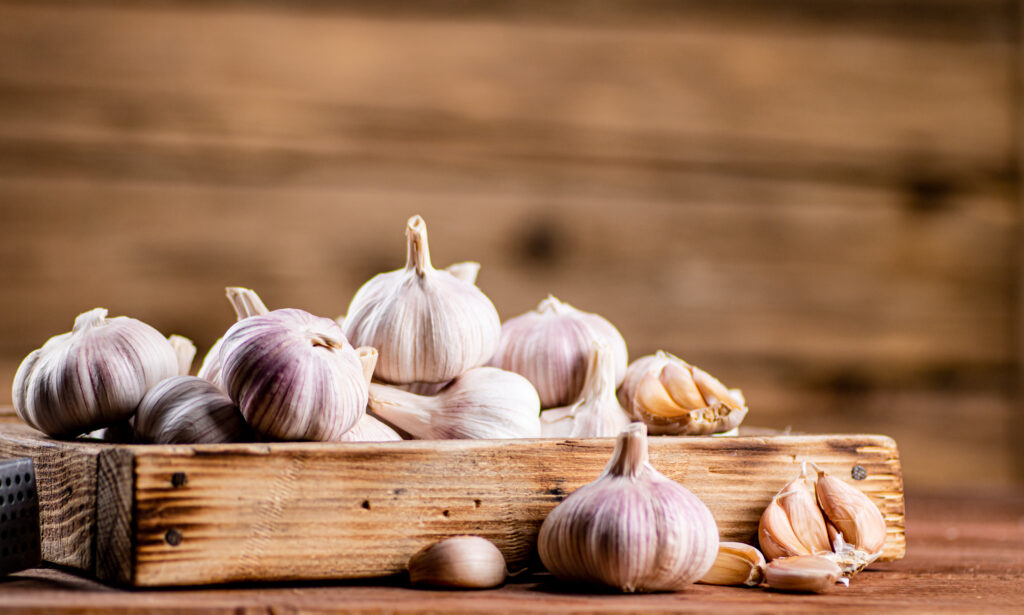 A pile of garlic on a wood tray