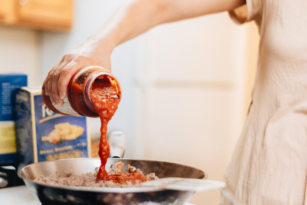 a person pouring sauce into a bowl