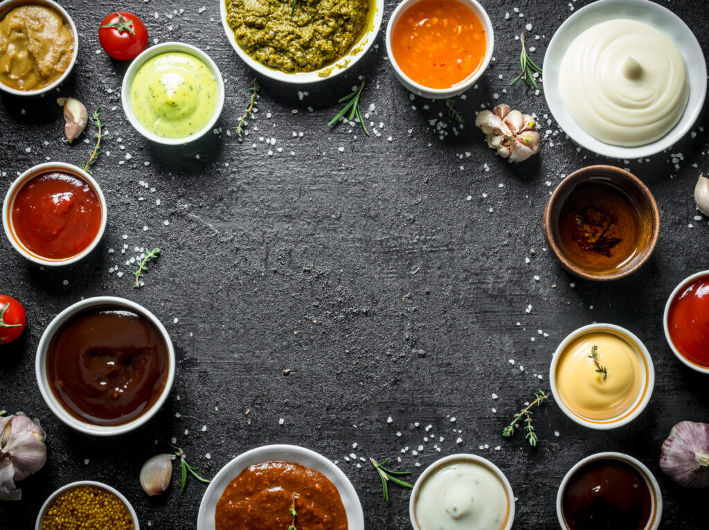 An array of chili sauces laid out next to ingredients on a table