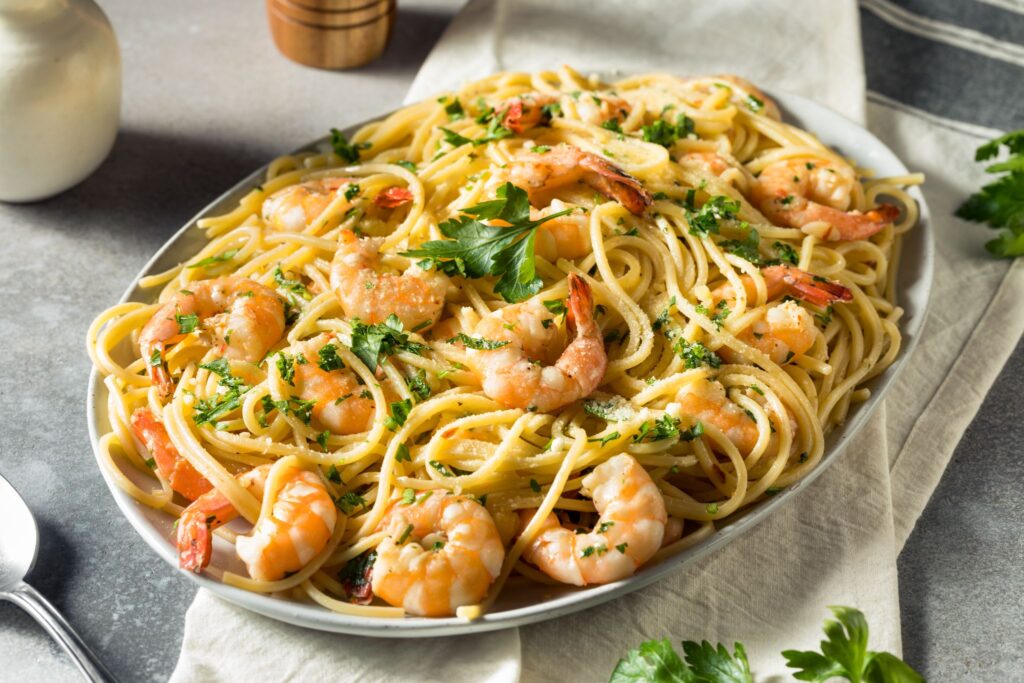 A plate of shrimp scampi resting on top of a cloth napkin.