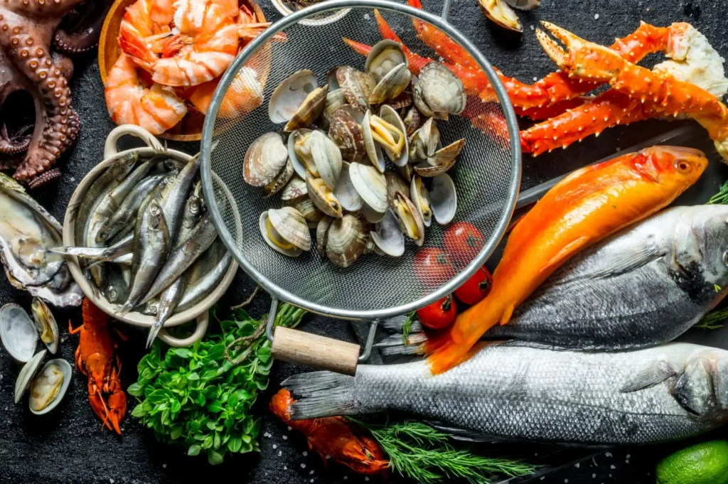 Clams, fish, crab, shrimp, and octopus in bowls on a black surface.