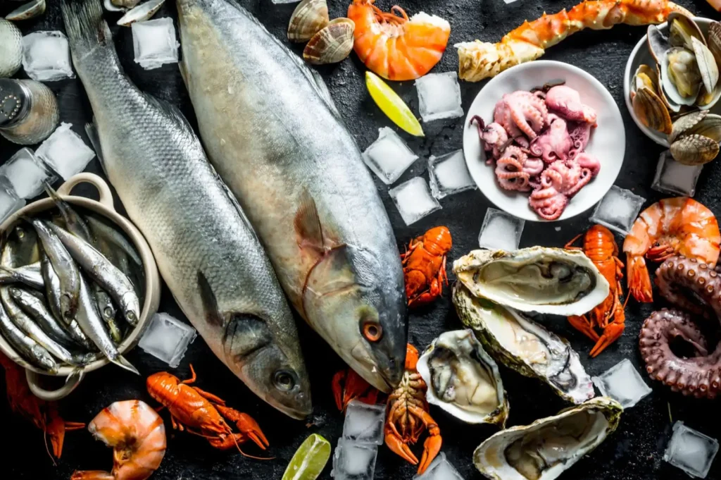 Fish, shrimp, octopus, and oysters surrounded by limes and ice cubes.