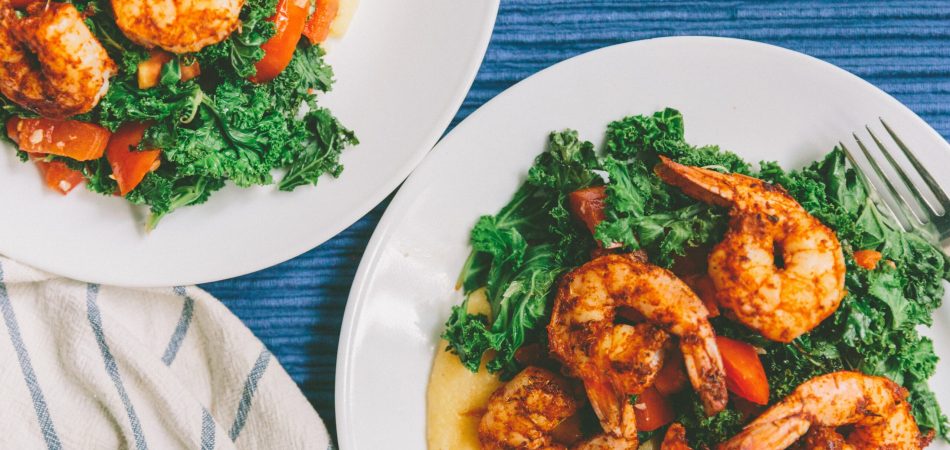 Two bowls of shrimp and grits on a blue corduroy tablecloth.