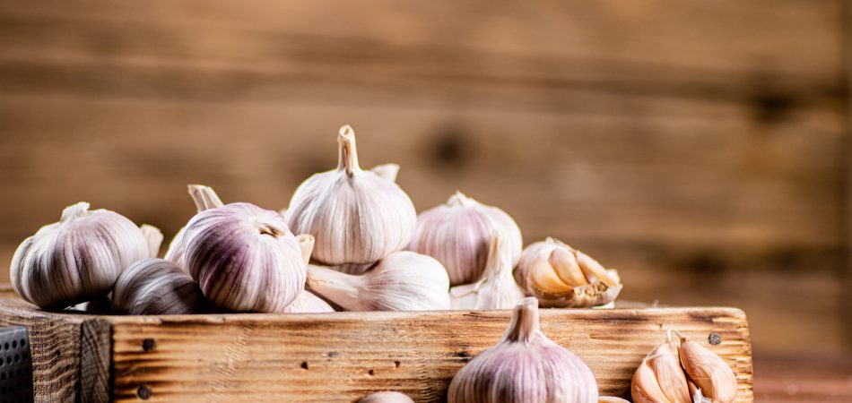 A pile of garlic on a wood tray