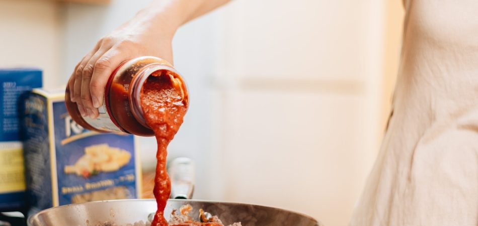 a person pouring sauce into a bowl